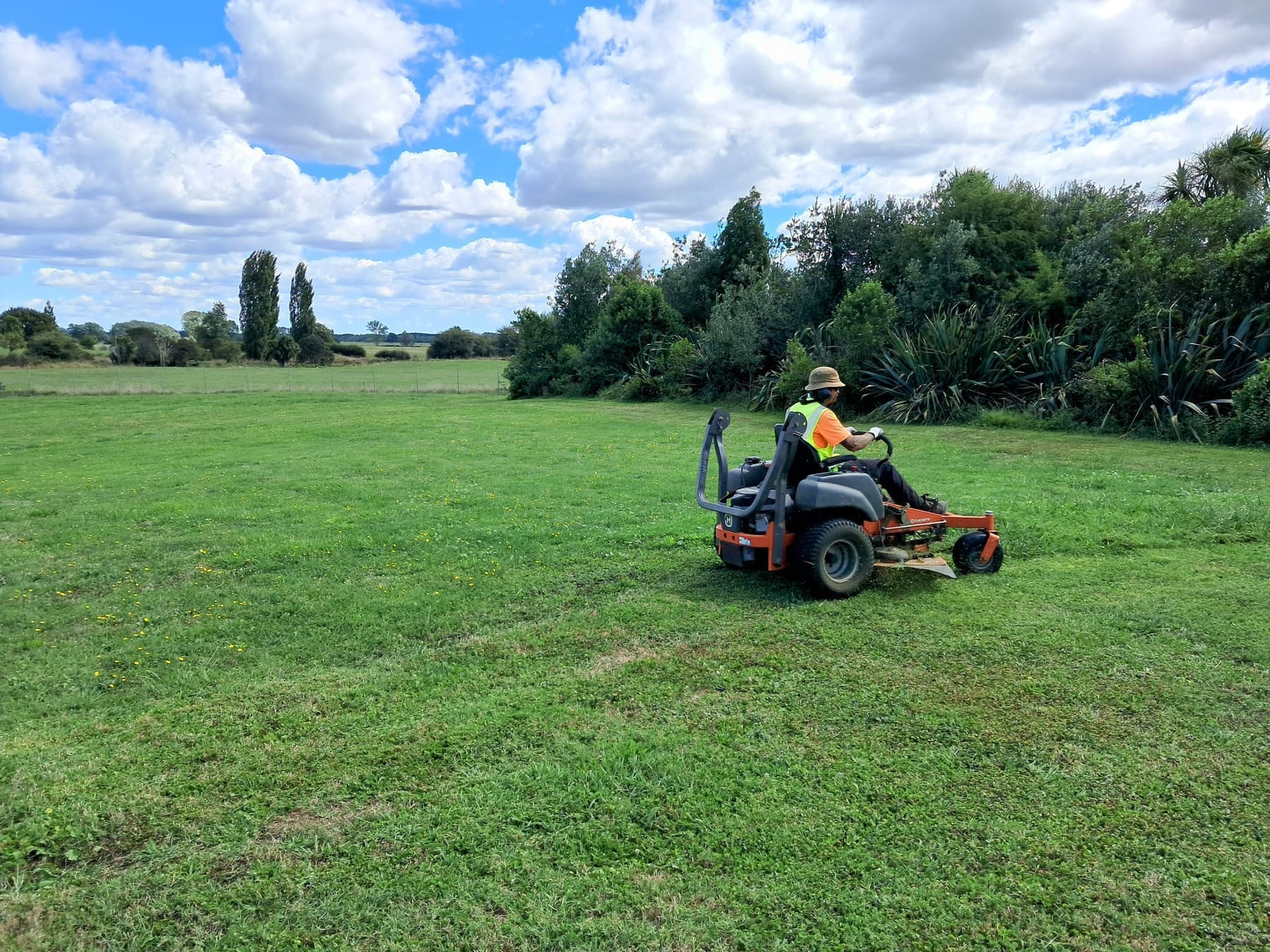 Zero-turn mower on rural block, bush edge